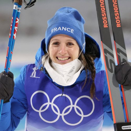 Anaïs Chevalier en tenue de sport, tenant des skis, souriante