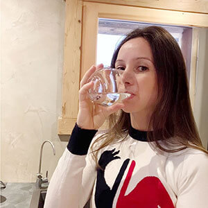 Anaïs Chevalier buvant un verre d’eau dans sa cuisine à domicile