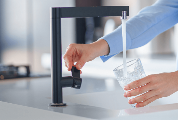 Personne remplissant un verre d’eau au robinet de la cuisine