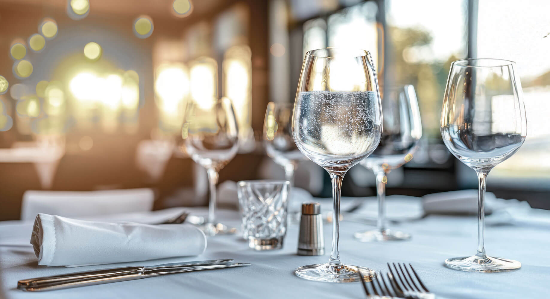 Table de restaurant dressée à l’intérieur avec lumière du soleil traversant les vitres